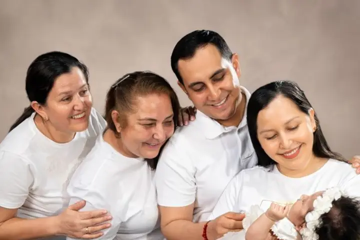 Una familia de tres generaciones sonriendo con un bebé recién nacido