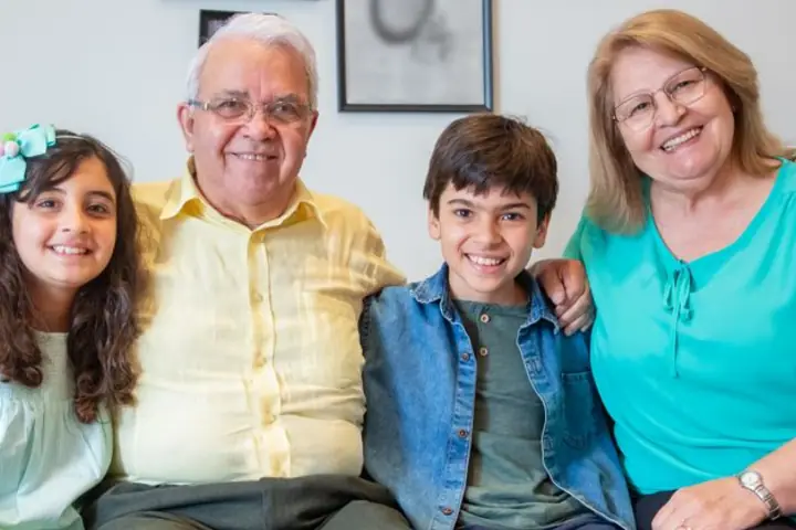 Un matrimonio mayor sonriendo en el sofá con sus dos nietos