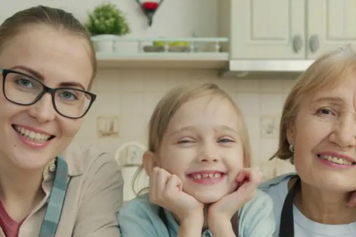 Una madre, su hija y la abuela sonriendo juntas en la cocina